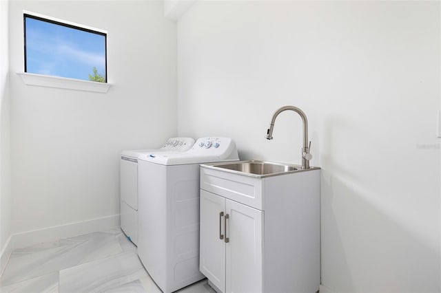 clothes washing area featuring sink, washing machine and dryer, and cabinets