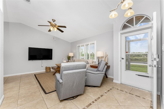 tiled living room featuring vaulted ceiling and ceiling fan with notable chandelier