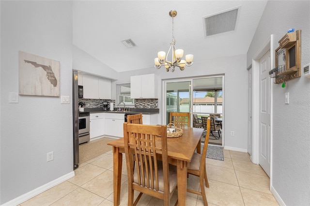 tiled dining area featuring vaulted ceiling, a chandelier, and sink