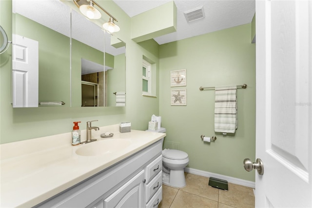 bathroom featuring tile patterned flooring, vanity, a shower with shower door, and toilet