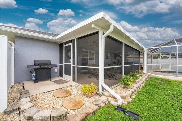 back of house featuring a patio area, a sunroom, and a lawn