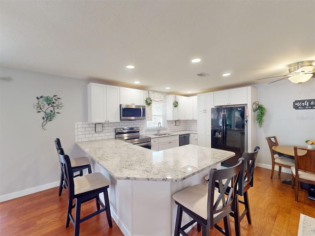 kitchen featuring white cabinetry, kitchen peninsula, sink, and black appliances