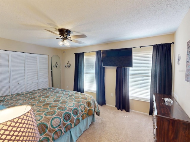 bedroom featuring light carpet, ceiling fan, multiple windows, and a textured ceiling