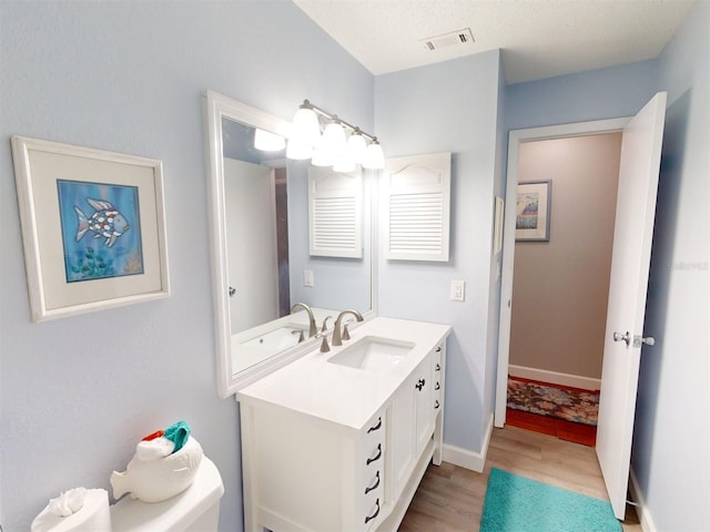 bathroom with vanity, toilet, and hardwood / wood-style floors