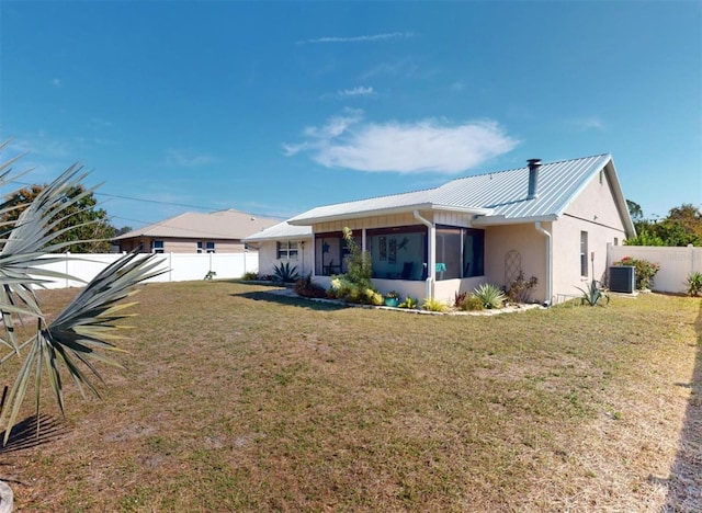 view of front of property with central AC, a front yard, and a sunroom