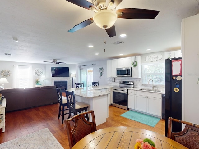 kitchen featuring stainless steel appliances, sink, wood-type flooring, and white cabinets