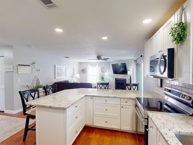 kitchen with white cabinetry, a breakfast bar, kitchen peninsula, and appliances with stainless steel finishes