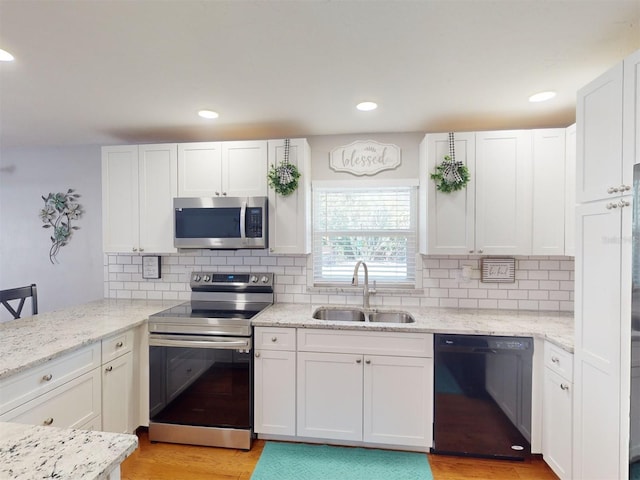 kitchen with appliances with stainless steel finishes, sink, white cabinets, and decorative backsplash