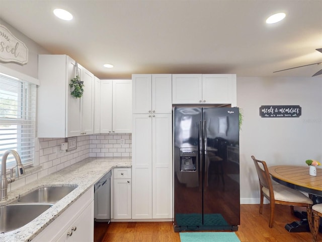 kitchen featuring black fridge, sink, and white cabinets