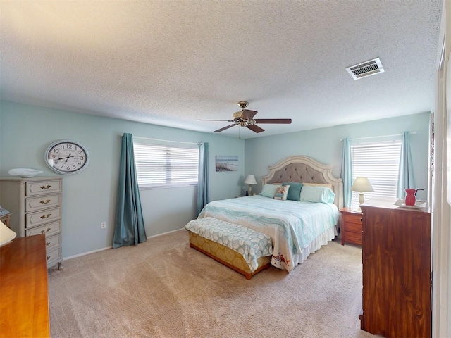 bedroom featuring light colored carpet, a textured ceiling, and ceiling fan