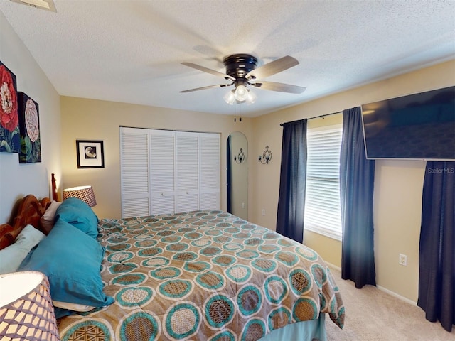 carpeted bedroom with ceiling fan, a closet, and a textured ceiling