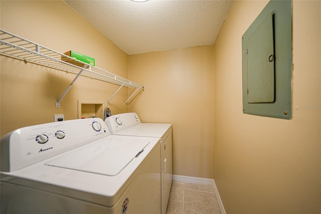 laundry room with washing machine and clothes dryer, light tile patterned floors, electric panel, and a textured ceiling