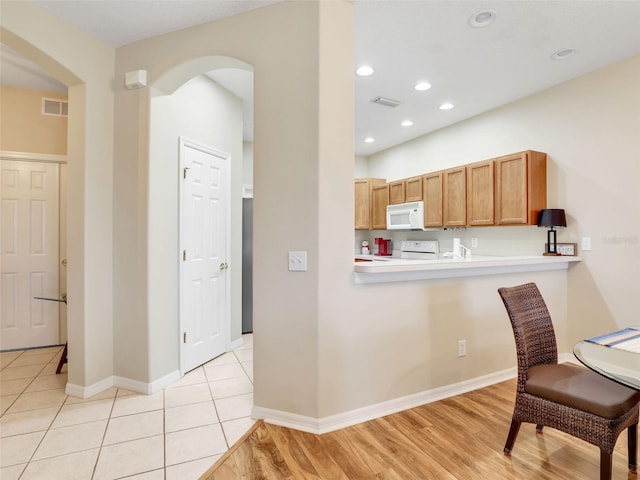 kitchen featuring kitchen peninsula, white appliances, and light hardwood / wood-style flooring