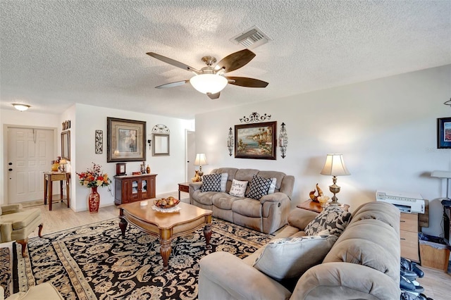 living room featuring ceiling fan, a textured ceiling, and light wood-type flooring