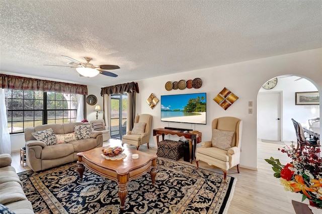 living room featuring a textured ceiling, ceiling fan, and light hardwood / wood-style flooring