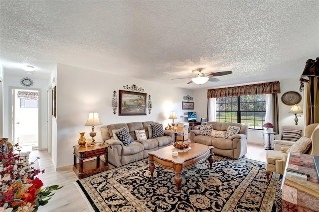 living room featuring ceiling fan, light hardwood / wood-style flooring, and a textured ceiling