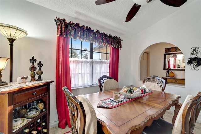 dining area featuring lofted ceiling, a textured ceiling, ceiling fan, and light wood-type flooring