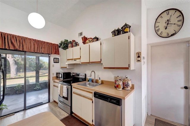 kitchen featuring hanging light fixtures, stainless steel appliances, light hardwood / wood-style floors, and high vaulted ceiling