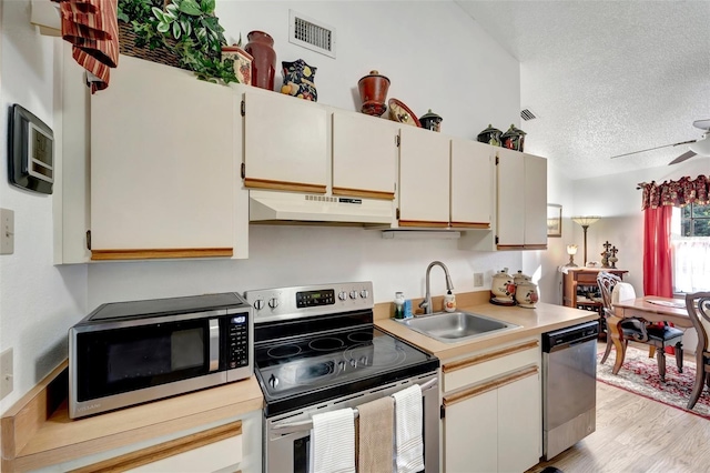 kitchen featuring sink, light hardwood / wood-style flooring, ceiling fan, stainless steel appliances, and a textured ceiling