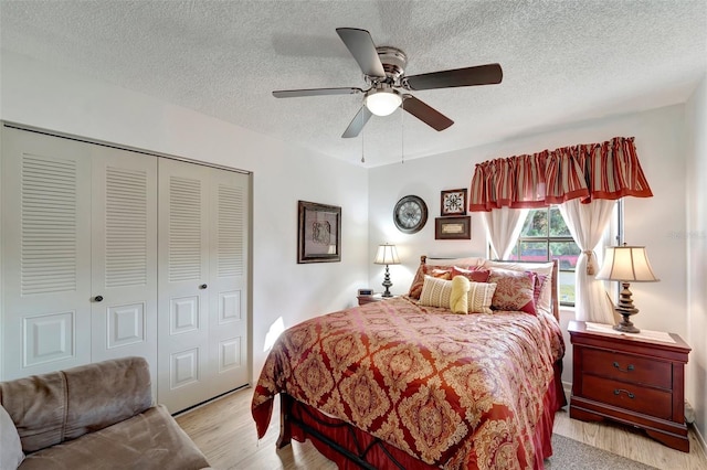 bedroom with ceiling fan, light hardwood / wood-style flooring, a closet, and a textured ceiling