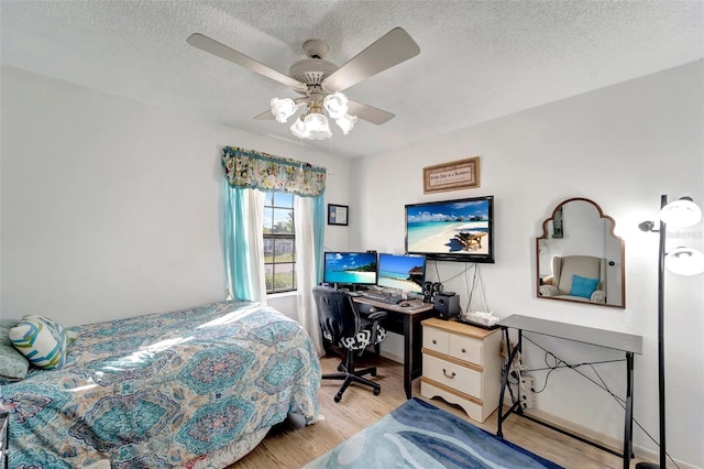 bedroom with ceiling fan, light hardwood / wood-style floors, and a textured ceiling