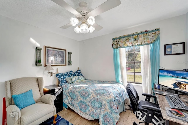 bedroom featuring ceiling fan, light hardwood / wood-style floors, and a textured ceiling