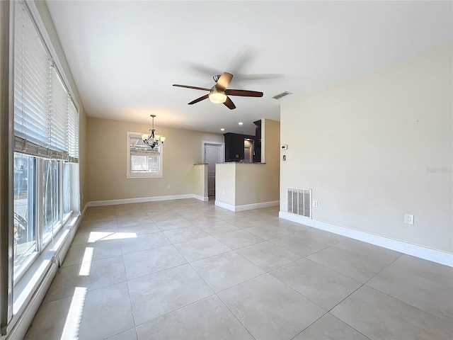 tiled empty room featuring ceiling fan with notable chandelier