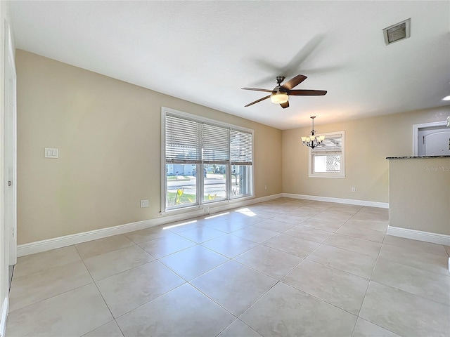 tiled spare room with ceiling fan with notable chandelier