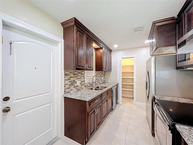 kitchen with tasteful backsplash, sink, dark brown cabinets, and appliances with stainless steel finishes