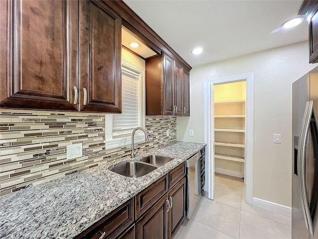 kitchen featuring sink, light stone counters, light tile patterned floors, stainless steel appliances, and decorative backsplash