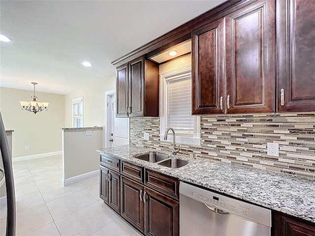 kitchen with sink, light stone countertops, light tile patterned flooring, decorative light fixtures, and stainless steel dishwasher