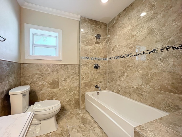 bathroom featuring crown molding, toilet, tiled shower / bath combo, and tile walls