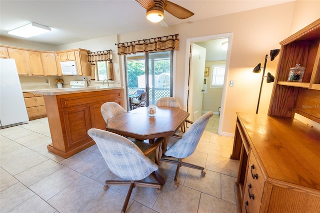 dining space with sink, light tile patterned floors, and ceiling fan