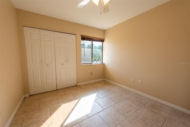 unfurnished bedroom with light tile patterned floors, ceiling fan, baseboards, and a closet