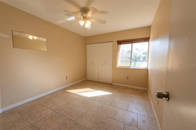 unfurnished bedroom featuring light tile patterned floors, a closet, a ceiling fan, and baseboards