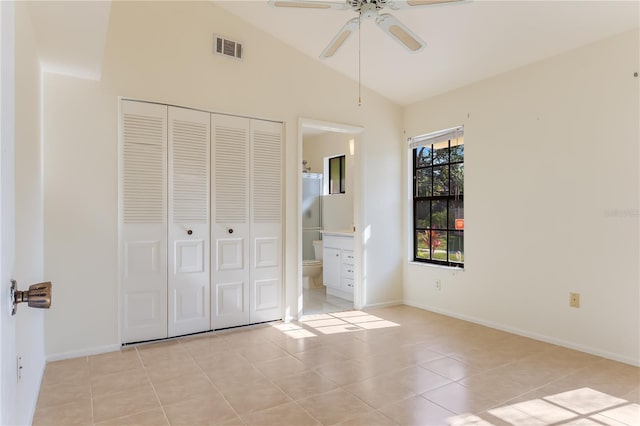 unfurnished bedroom featuring lofted ceiling, light tile patterned floors, ensuite bath, and a closet