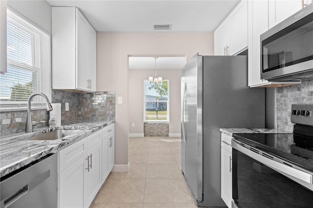 kitchen featuring sink, white cabinets, light tile patterned floors, stainless steel appliances, and light stone countertops