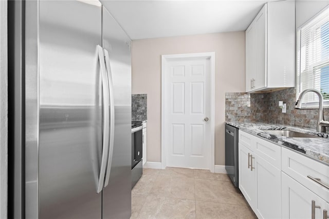 kitchen with tasteful backsplash, white cabinetry, sink, stainless steel appliances, and light stone countertops