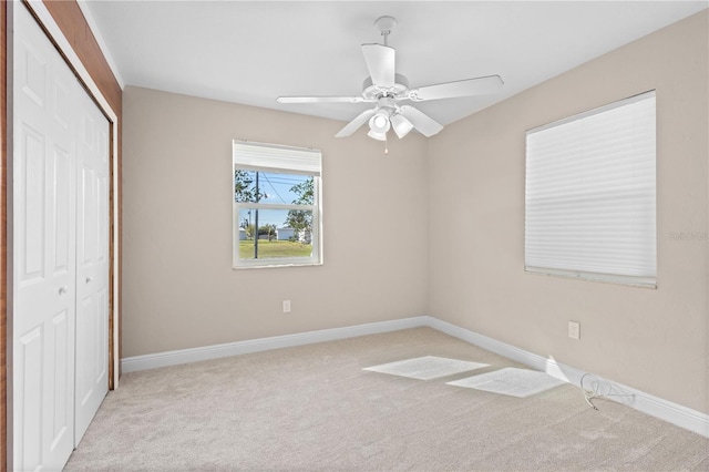 unfurnished bedroom featuring light carpet, a closet, and ceiling fan