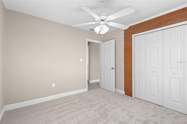 unfurnished bedroom featuring ceiling fan, light colored carpet, and a closet