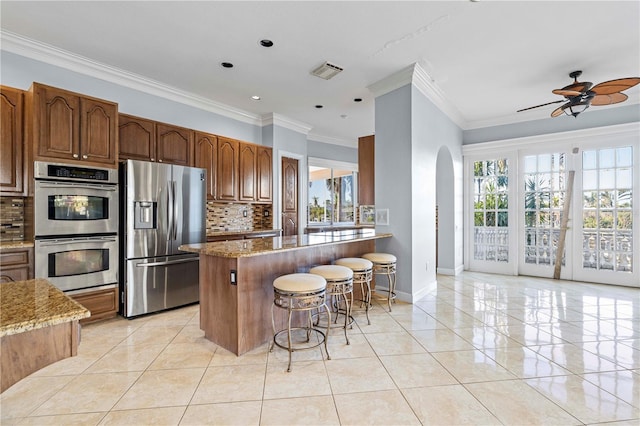 kitchen with light stone counters, a wealth of natural light, a kitchen breakfast bar, and appliances with stainless steel finishes