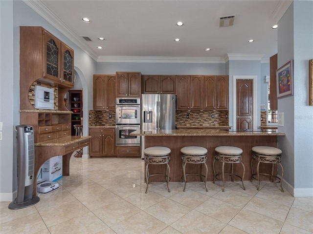 kitchen with ornamental molding, appliances with stainless steel finishes, light stone counters, and decorative backsplash