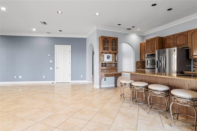 kitchen with light tile patterned floors, crown molding, backsplash, a kitchen breakfast bar, and stainless steel fridge with ice dispenser