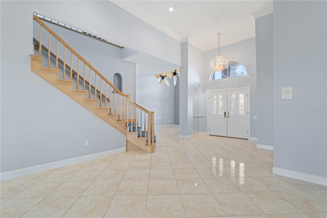 tiled entrance foyer featuring an inviting chandelier, ornamental molding, french doors, and a high ceiling