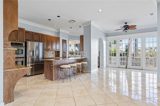 kitchen with a wealth of natural light, a breakfast bar, dark stone counters, and appliances with stainless steel finishes