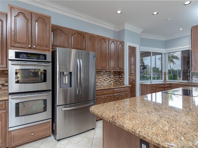 kitchen featuring light tile patterned flooring, light stone counters, ornamental molding, appliances with stainless steel finishes, and decorative backsplash