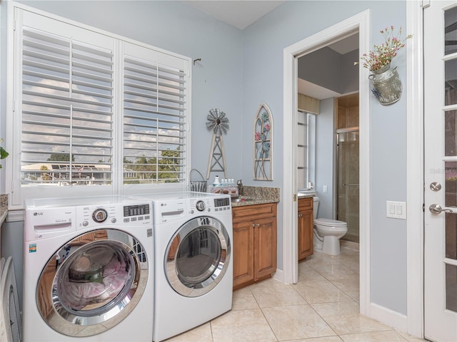 washroom featuring light tile patterned floors, washing machine and dryer, and cabinets