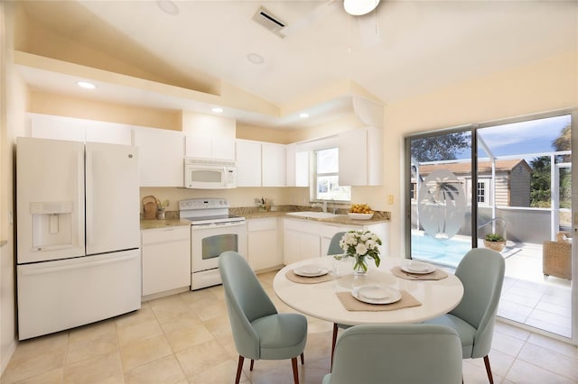 kitchen featuring sink, white appliances, white cabinets, light tile patterned flooring, and vaulted ceiling