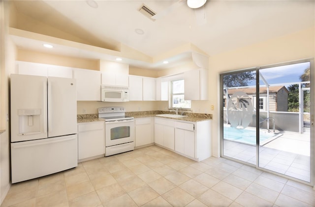 kitchen featuring sink, white appliances, light tile patterned floors, white cabinets, and vaulted ceiling