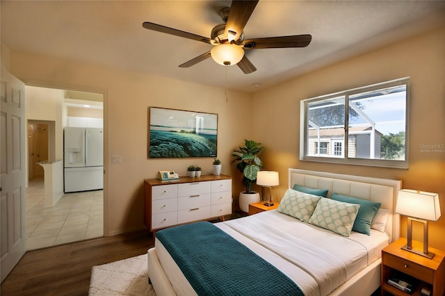 bedroom with ceiling fan, white refrigerator with ice dispenser, and light wood-type flooring